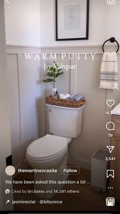 a white toilet sitting in a bathroom next to a wooden cabinet and sink with a mirror above it