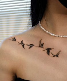 a woman's chest with birds flying in the air on her left shoulder and right arm