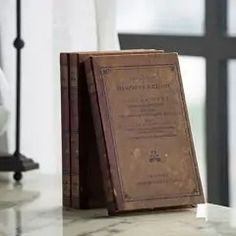 an old book sitting on top of a table next to a lamp and window sill