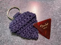 a purple knitted hat with a triangle shaped keychain sitting on top of it