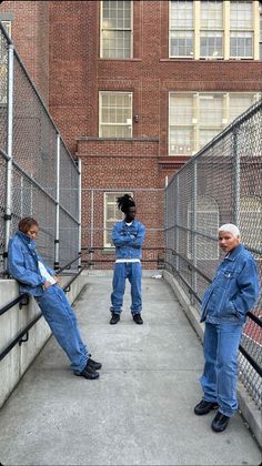 three people are sitting on the side of a fenced in area and one person is standing