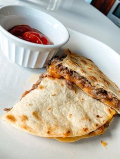 two quesadillas on a plate with ketchup in a small bowl