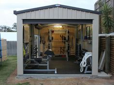 a garage with an open door and lots of exercise equipment in the back yard area