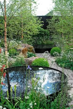 a garden with a pond surrounded by trees and flowers