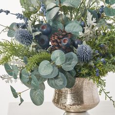 a vase filled with blue flowers and greenery