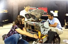 two men and a woman looking at an old camera