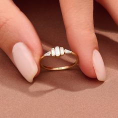 a woman's hand with white nails and gold ring on top of her finger