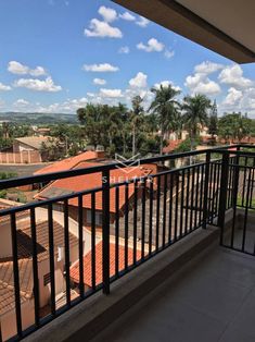 a balcony with black iron railings and red tiled roofing, overlooking palm trees