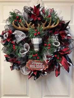 a christmas wreath with antlers and ribbons hanging on the front door to welcome guests