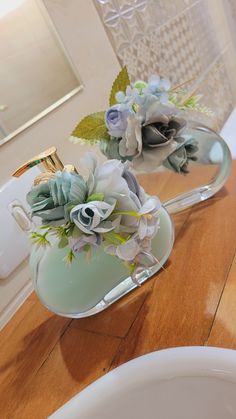 two glass vases with flowers in them sitting on a table next to a mirror