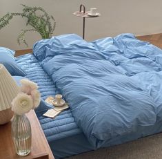 a bed that has been made with blue sheets and pillows on top of the bed