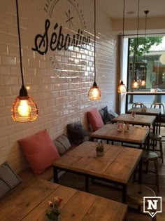 an empty restaurant with wooden tables and benches in front of a window that reads sebbin