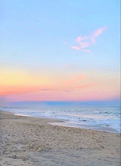 two people are walking on the beach with their surfboards in hand as the sun sets