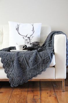 a couch with a knitted blanket on top of it and a coffee cup in the middle