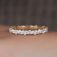 a woman's hand with a yellow gold band and diamond ring on her arm