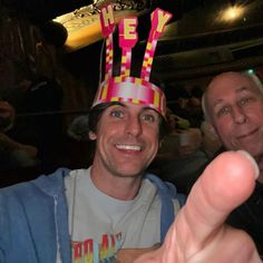 two men wearing party hats and pointing at the camera