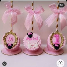 three pink cupcakes with gold trim and bows