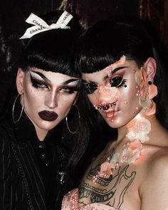 two women with makeup on their faces posing for the camera