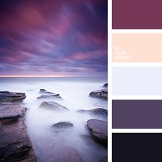 some rocks and water under a purple sky with white clouds in the background at dusk