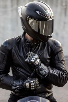 a man in black leather jacket and helmet riding a motorcycle