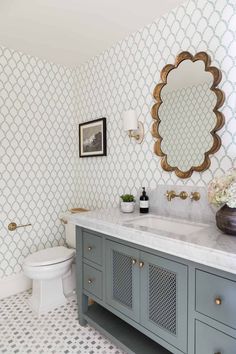 a white toilet sitting next to a bathroom sink under a large mirror on top of a wall