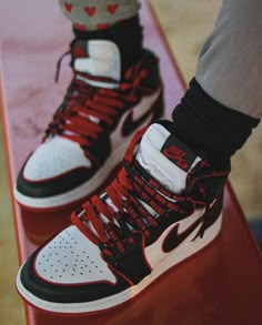 a person standing on top of a skateboard with red and white shoes attached to it