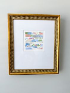 a gold frame hanging on the wall with a painting in it's center and bottom corner