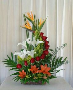 an arrangement of flowers and greenery on a table