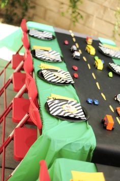 a long table topped with plates and cups filled with candy bar wrappers on top of a black table cloth