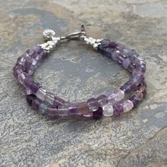 This fluorite bracelet features 2 strands of natural, faceted fluorite cubes. Most all of the cubes are in purple tones. There are even a few blues! No Greens.  Strung on quality stainless steel beading wire and closes with a sterling silver Hill Tribe toggle clasp. A sterling silver flower bud charm sits at the clasp. 7.5 inch bracelet Fluorite cube alone: 4 x 4mm Your jewelry will arrive in a cotton lined kraft box within a padded postal envelope. I use USPS first class mail. This usually takes 3 to 5 days to ship. International orders outside of the U.S. will take 8 to 15 days to ship. To see more from East Village Jewelry~ http://eastvillagejewelry.etsy.com All orders ship out within 24 hours, excluding holidays and Sundays Feel free to contact me with any questions. Use coupon code VI Sunday Feels, Fluorite Bracelet, Purple Tones, Labradorite Necklaces, East Village, Agate Bracelet, Double Ring, Beading Wire, Sterling Silver Flowers