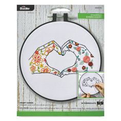 the embroidery kit has two hands making a heart