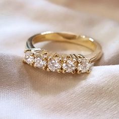 a gold ring with five diamonds on it