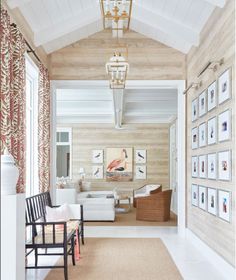 a living room filled with white furniture and pictures on the wall above it's doorway