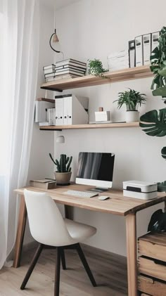 a desk with a computer and some plants on it