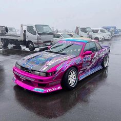 a pink car parked on top of a wet parking lot