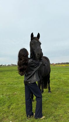 a woman holding the back of a black horse