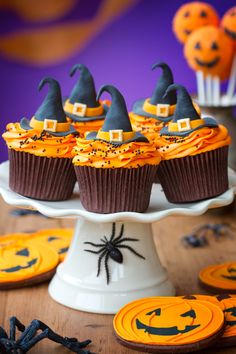 cupcakes decorated with chocolate frosting and halloween decorations sit on a cake plate