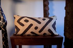 a giraffe print pillow sitting on top of a wooden chair next to a pair of leggings