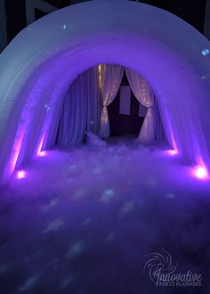 an inflatable tunnel with purple lights on the sides and white drapes around it