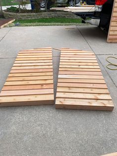 two pieces of wood are laying on the ground in front of a car parked outside