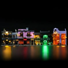 a group of buildings lit up at night with lights reflecting off the water in front of them