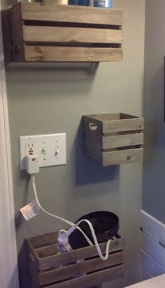 a bathroom with two wooden crates on the wall and an electrical outlet plugged in