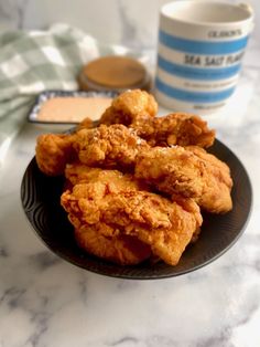 fried chicken on a black plate next to a cup