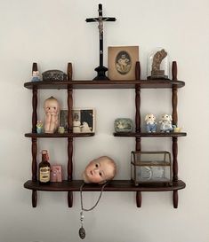 there is a shelf with dolls and other items on it in the corner next to a crucifix