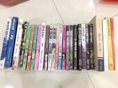 a bunch of books are lined up on the floor next to a red plastic object