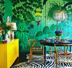 a dining room decorated in green and yellow with zebra print on the floor, wallpaper