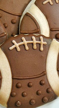 decorated cookies in the shape of footballs with chocolate icing and white frosting