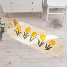 a rug with yellow tulips on it next to a white dresser and chair