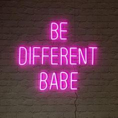 a pink neon sign that says be different babe on a brick wall in the dark