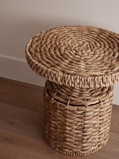 a wicker basket on the floor next to a wall